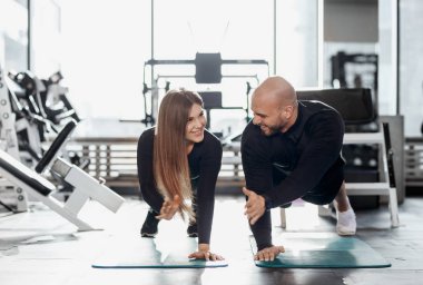 Acımasız atletik adam ve ince kız siyah sıralar kıyafetlerini giyinmiş genç modern spor salonu ile büyük pencereler tahta yapıyoruz