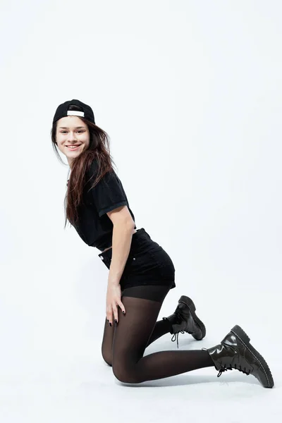 Premium Photo  Stylish dark-haired girl dressed in a black t-shirt, shorts,  tights and cap is posing on the white background in the studio .