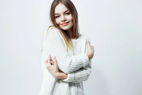 Beautiful long-haired girl in a white knitted sweater is posing on the white background in the studio — Stock Photo, Image