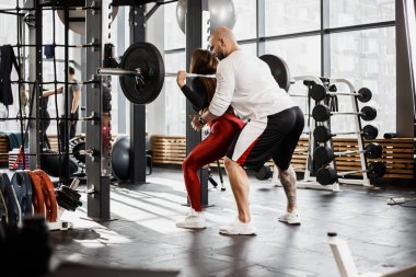 Atletik şık parlak arka ağız kavgası yapıyor giyim spor kız ve güçlü atletik adam onu modern spor salonunda yardımcı olur