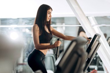 Spor salonunda bir koşu bandı üzerinde siyah spor giyim iş dışarı giyinmiş ince esmer kız