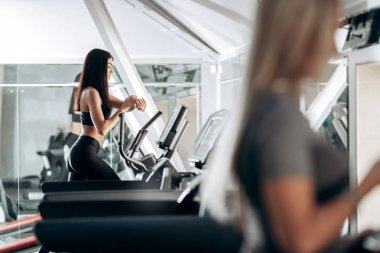 Spor salonunda bir koşu bandı üzerinde siyah spor giyim iş dışarı giyinmiş ince esmer kız