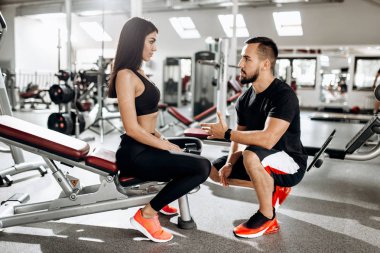 Koç atletik kızı spor salonunda bankta oturmuş siyah spor elbise giymiş ile görüşmeler