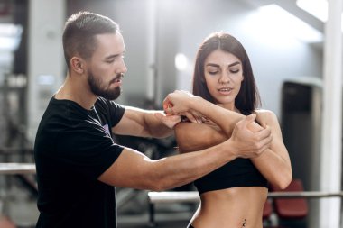 Fitness antrenörü explans atletik kıza nasıl siyah spor kıyafetlerini giymiş kas silah çalışır