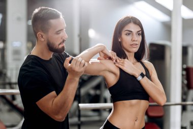 Fitness antrenörü explans atletik kıza nasıl siyah spor kıyafetlerini giymiş kas silah çalışır