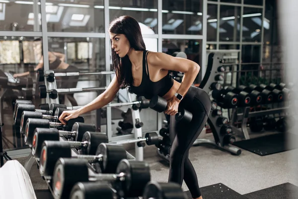 İnce kız siyah spor kıyafetlerini giymiş dayanıklılık egzersiz halter salonunda ile yapıyor — Stok fotoğraf