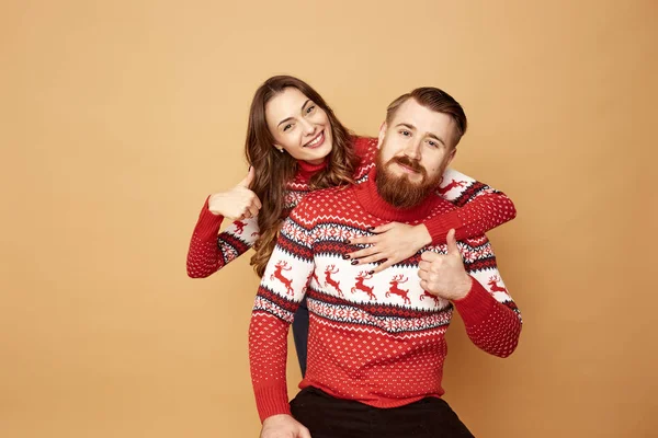 Ragazza divertente e un ragazzo vestito con maglioni rossi e bianchi con cervo stare insieme su uno sfondo beige in studio — Foto Stock