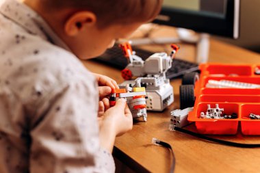 Akıllı çocuk gri gömlek giymiş bir robot Robotik okul masasında robot Oluşturucu yapar