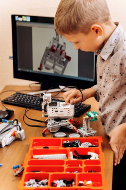 Akıllı çocuk gri gömlek giymiş bir robot Robotik okul bilgisayar ile masada robot Oluşturucu yapar