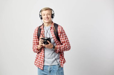 Kulaklık, Beyaz tişört, kırmızı kareli gömlek ve kot pantolon giymiş onun omuz siyah sırt çantası ile sarışın adam beyaz zemin üzerine onun elinde kamera tutan