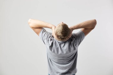 Sarışın adam ellerini başını stüdyoda beyaz arka planda tutan Beyaz tişört giymiş arkadan görünüm