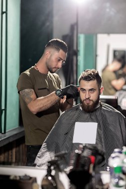 Acımasız adam aynaya bir kuaför salonu önünde oturur. Kuaför saç kesim yapar.