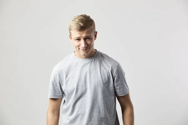 Ler blond kille klädd i en vit t-shirt står på den vita bakgrunden i studion — Stockfoto