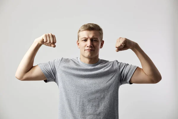 Full av makt blond kille klädd i en vit t-shirt står på den vita bakgrunden i studion — Stockfoto