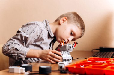 Çocuk gri gömlek giymiş bir robot Robotik okul masasında robot Oluşturucu yapar