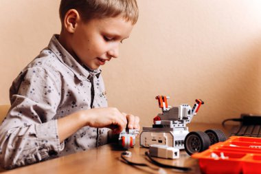 Çalışkan çocuk gri gömlek giymiş bir robot Robotik okul masasında robot Oluşturucu yapar