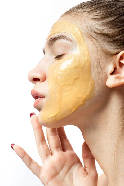 Het gezicht van een jong meisje met gele cosmetische masker op het — Stockfoto