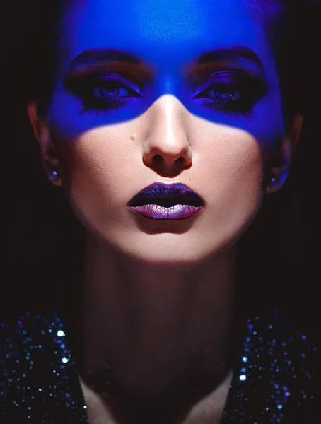 Porträt eines Mode-Mädchens mit stylischem Make-up und blauem Neonlicht im Gesicht auf schwarzem Hintergrund im Studio — Stockfoto