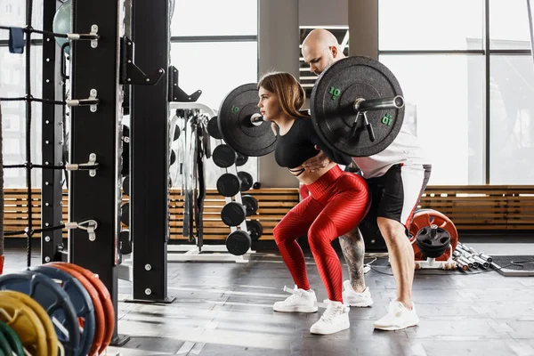 Atletik şık parlak arka ağız kavgası yapıyor giyim spor kız ve güçlü atletik adam onu modern spor salonunda yardımcı olur