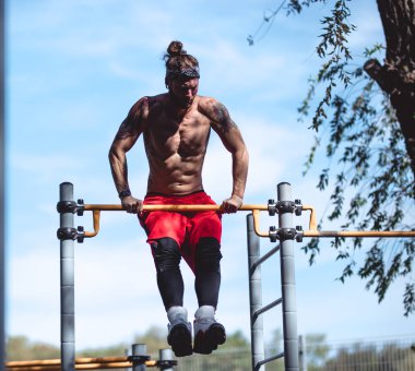 Siyah tayt ve dışında spor çubuğunda yükselişte zemin kırmızı şort yapar kafa bandı çıplak gövde ile atletik adam giymiş