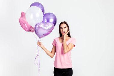 Sürpriz kız pembe t-shirt ve jeans giymiş beyaz arka plan stüdyo ellerinde balonlar tutar