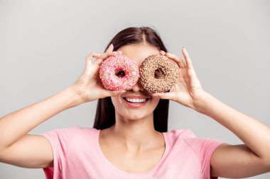 Gözleri bir gözlük beyaz zemin üzerine gibi yakınındaki iki parlak ağız sulandıran donut pembe gömlek giymiş kız tutar