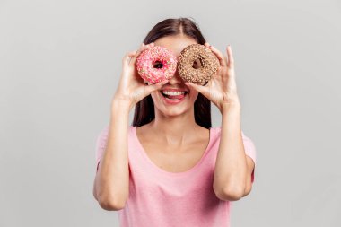 Gözleri bir gözlük beyaz zemin üzerine gibi yakınındaki iki parlak ağız sulandıran donut pembe gömlek giymiş kız tutar