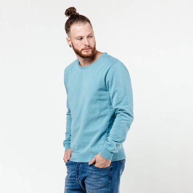 Studio beyaz arka plan üzerine açık mavi uzun kollu kazak ve kot pozlar giymiş sakal ve topuz saç modeli ile şık adam