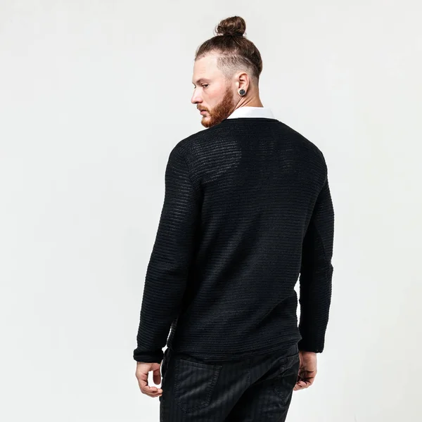 Homme élégant avec coiffure barbe et chignon portant un pull noir sur une chemise blanche et des poses de pantalon dans le studio sur le fond blanc — Photo