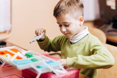 Robot Oluşturucu ayrıntıları ile açılan kutusunu tabloyla yeşil Kazak giymiş çocuk oturur