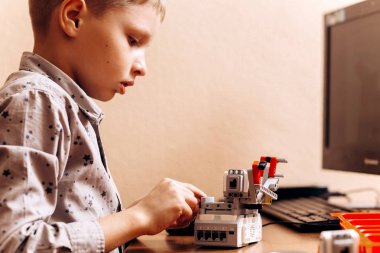Akıllı çocuk gri gömlek giymiş bir robot Robotik okul bilgisayar ile masada robot Oluşturucu yapar