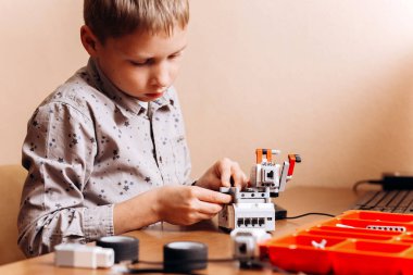 Çocuk gri gömlek giymiş bir robot Robotik okul masasında robot Oluşturucu yapar
