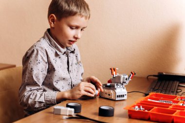 Çalışkan çocuk gri gömlek giymiş bir robot Robotik okul masasında robot Oluşturucu yapar