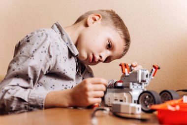 Çalışkan çocuk gri gömlek giymiş bir robot Robotik okul masasında robot Oluşturucu yapar