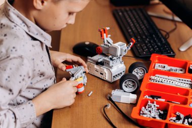 Akıllı çocuk gri gömlek giymiş bir robot Robotik okul masasında robot Oluşturucu yapar