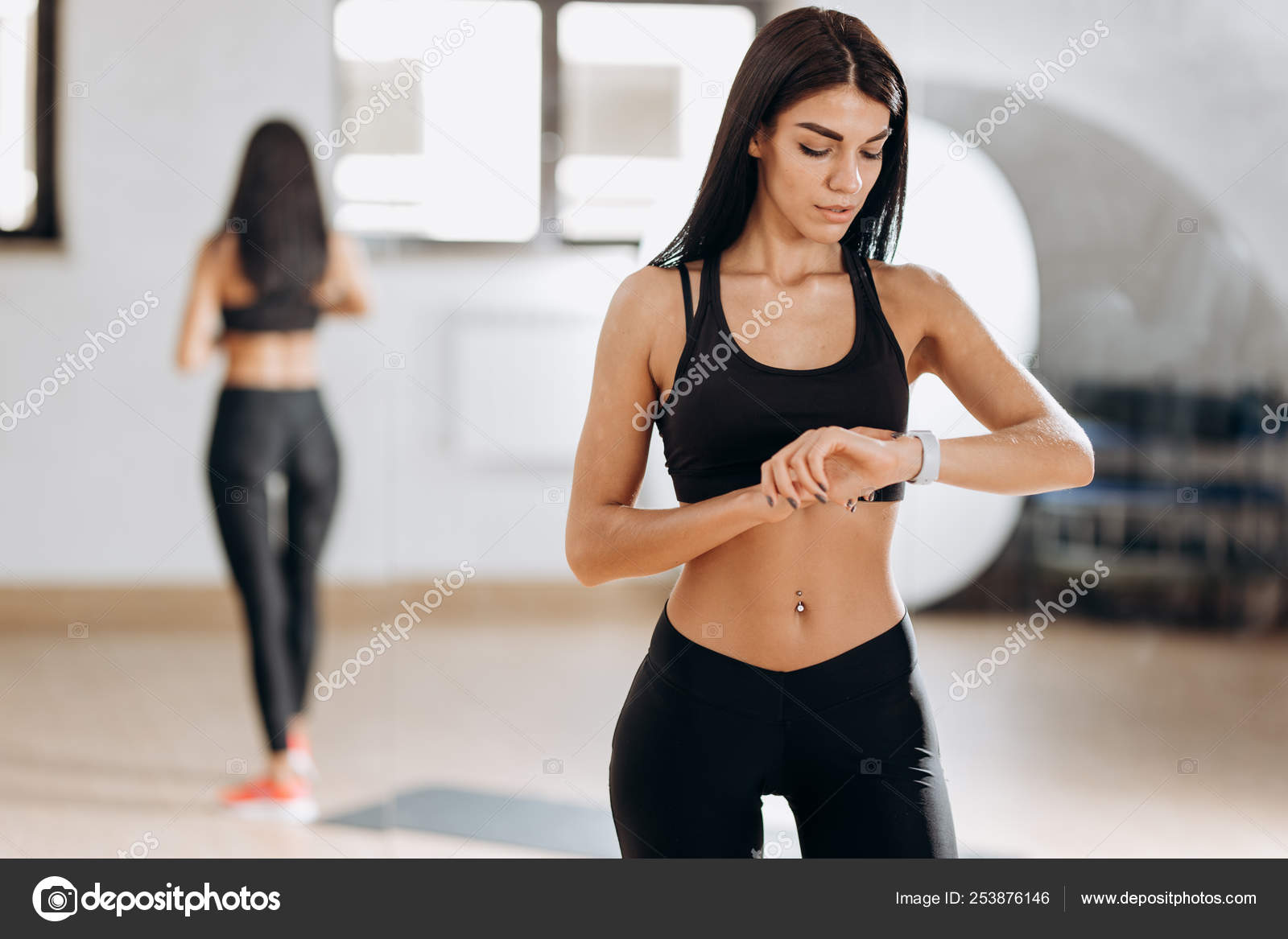 Beautiful slim girl dressed in black sportswear is standing in the gym in  the fitness room next to the mirror Stock Photo by ©Leika_production  253876146