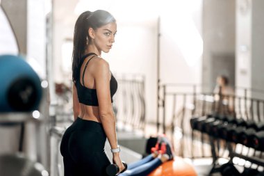 Atletik kız siyah spor top ve tayt giymiş halter salonunda ellerini tutar