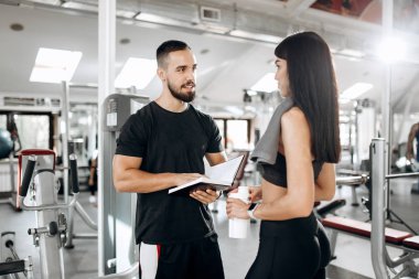 Esmer atletik kız siyah spor salonunda Spor hocası ile üst ve tayt görüşmeler giyinmiş