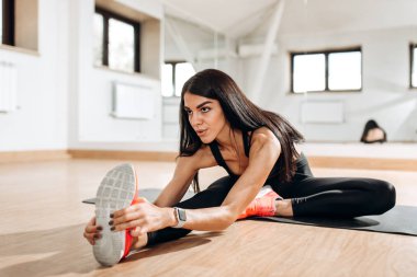 İnce kız siyah spor top ve tayt giymiş fitness salonunda fitness mindere germe yapıyor