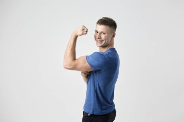 Mavi t-shirt giymiş adam güç ve enerji dolu hissediyorum. Beyaz arka plan üzerinde atış stüdyo