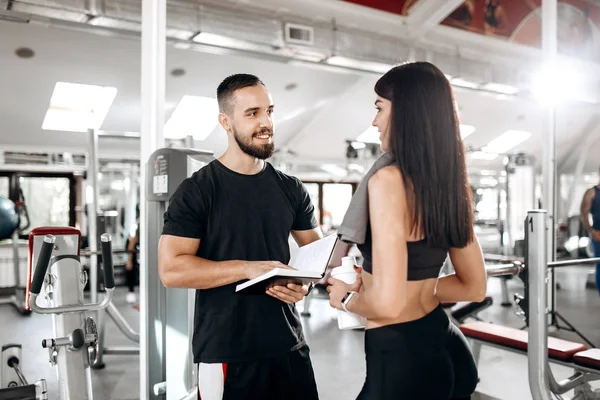 Spor salonunda spor hocası ile siyah spor top ve onun boyun görüşmeler havluda tayt giymiş esmer atletik kız