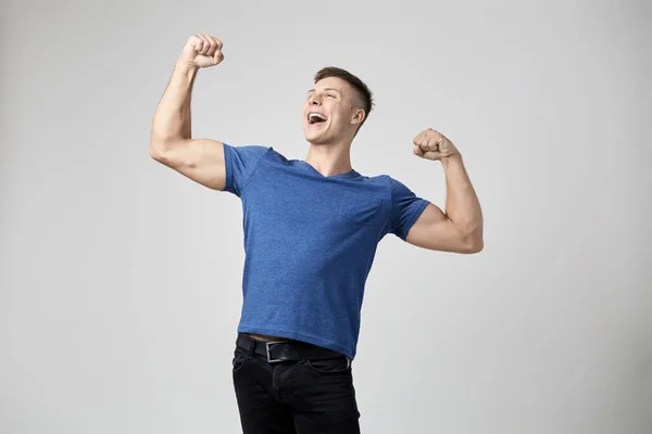 O cara vestido de camiseta azul se sente cheio de força e energia. Estúdio tiro no fundo branco — Fotografia de Stock