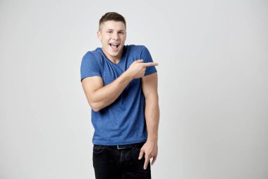 Neşeli adam mavi t-shirt Puan parmağını tarafa giyinmiş.