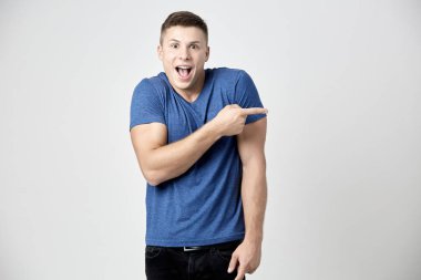 Neşeli adam mavi t-shirt Puan parmağını tarafa giyinmiş.