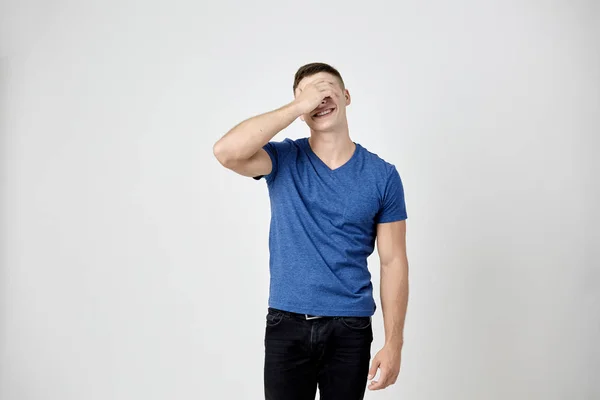 Killen klädd i blå t-shirt känns blyg och sluter sina ögon med handen — Stockfoto