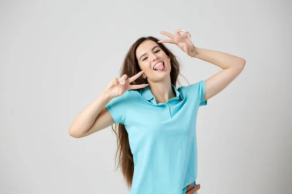 Chica feliz vestido de azul claro camiseta sonríe y muestra V signo — Foto de Stock