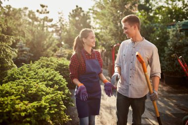 Bahçıvanlar güzel kız önlük ve güneşli bir günde harika Bahçe Bahçe yolda yürürken bir kürek ile adam