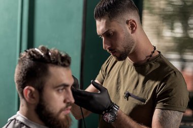 Sakallı acımasız yakışıklı adam bir berber dükkanında oturur. Kuaför tarafında bir trim yapar.