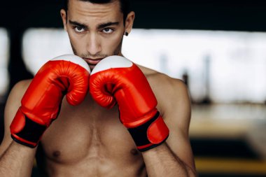 Sporcu çıplak bir gövde ile ellerini yüzüne boks jimnastik salonu yanındaki kırmızı boks eldivenleri tutar