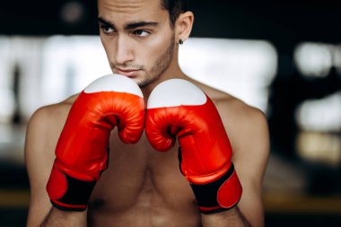 Sporcu çıplak bir gövde ile ellerini yüzüne boks jimnastik salonu yanındaki kırmızı boks eldivenleri tutar